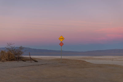 Road sign against sky during sunset