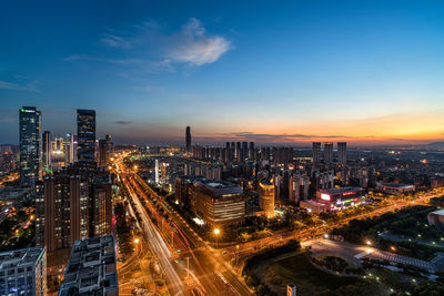 Illuminated cityscape against sky during sunset