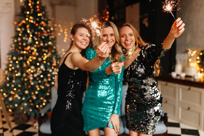 A group of happy people girls friends are having fun at a christmas party in a cozy decorated house