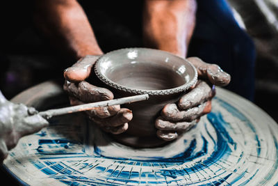 Cropped hands making pot on pottery wheel