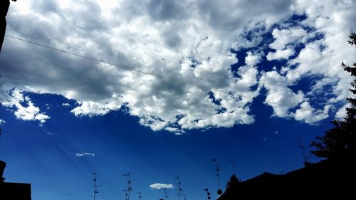 Low angle view of silhouette trees against cloudy sky