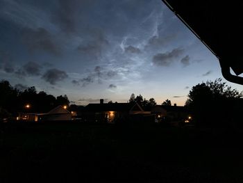 Silhouette trees and buildings against sky at night