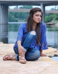 Portrait of young woman sitting by lake