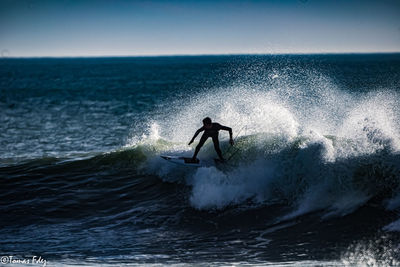 Man surfing in sea against sky