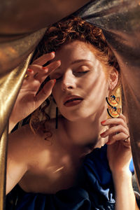 Portrait of young woman under a gold sheet