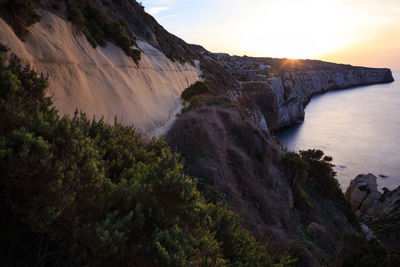 Scenic view of mountains by sea against sky during sunset