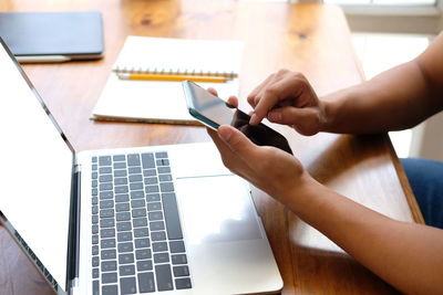 Midsection of woman using mobile phone on table