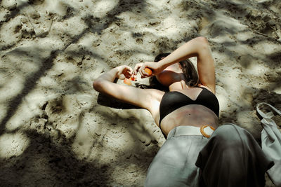 Low section of woman sitting on sand at beach