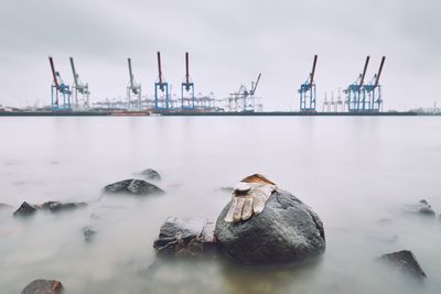 Cranes at harbor against sky