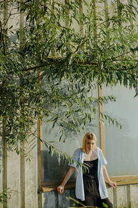 Woman standing by tree against plants