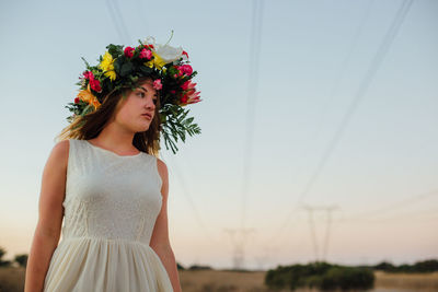 Young woman standing on field against sky