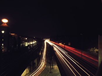 Light trails on road against sky at night