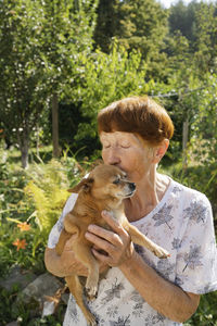 Senior woman kissing dog in garden