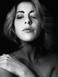 Close-up portrait of a beautiful young woman over black background