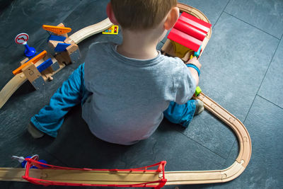 High angle view of boy playing with train set on floor at home