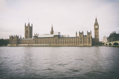 View of buildings by river against sky in city