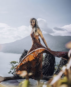 Portrait of woman in dress on lookout tower against mountain
