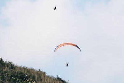 Low angle view of person paragliding against sky