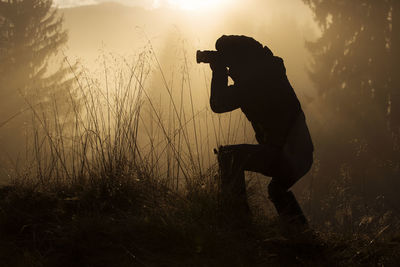 Side view of man photographing against sky