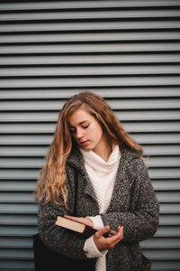 Beautiful young woman standing against wall