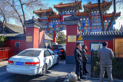 Rear view of people standing on street against buildings