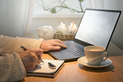 Midsection of woman using laptop on table