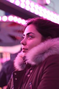Close-up of young woman in warm clothing standing outdoors at night