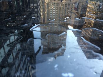 Buildings reflecting on wet footpath in city during rainy season