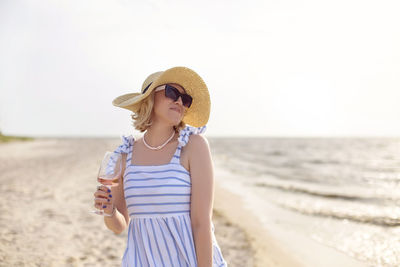 Young woman wearing hat while standing on beach