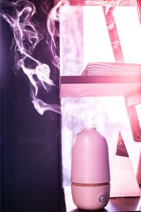 Close-up of glass bottle against pink background