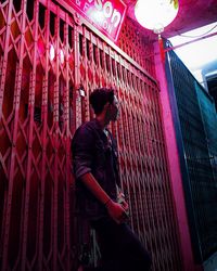 Side view of young man standing against railing