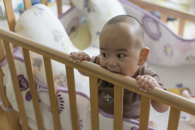 High angle view of cute baby boy sitting in crib