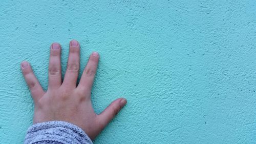 Cropped image of hand against green wall