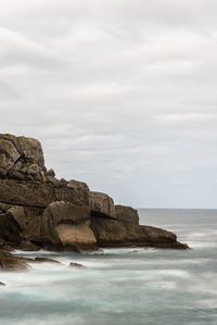 Rocks on sea shore against sky