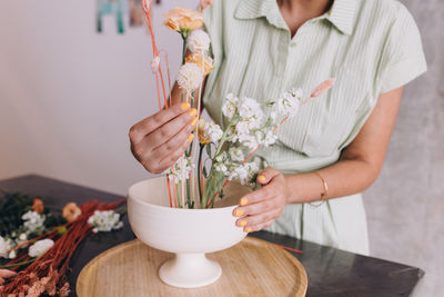 Midsection of woman holding vase, working on a ikebana center piece