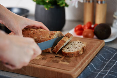 Woman cutting loaf of bread with large knife