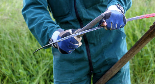 Midsection of man working on grassy field