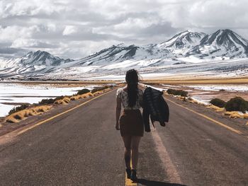 Rear view of woman on snowcapped mountain against sky