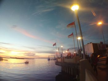 People on sea against sky during sunset