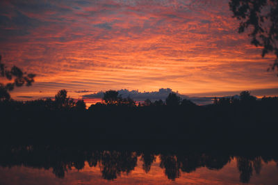 Reflection of trees in lake at sunset