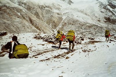 Rear view of people walking on snowcapped mountain