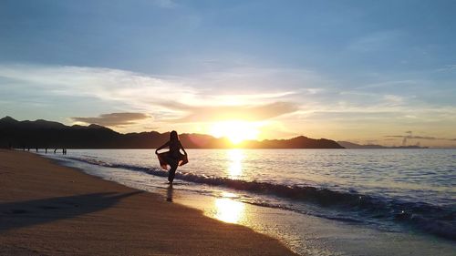 Man on beach against sky during sunset