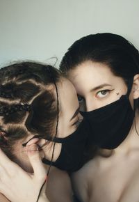 Close-up portrait of lesbian women embracing while wearing mask