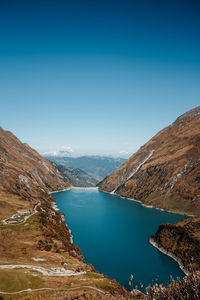 Scenic view of sea and mountains against clear blue sky