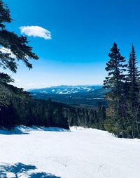 Scenic view of snow covered mountains against blue sky