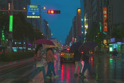 People walking on wet road in city during rainy season