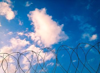 Low angle view of barbed wire against sky