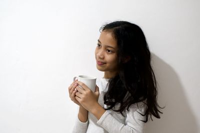 Mid adult woman holding drink against white background