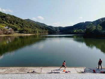 People on lake against sky