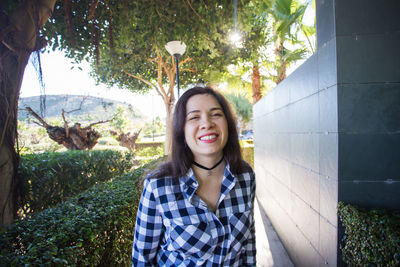 Portrait of smiling young woman against trees